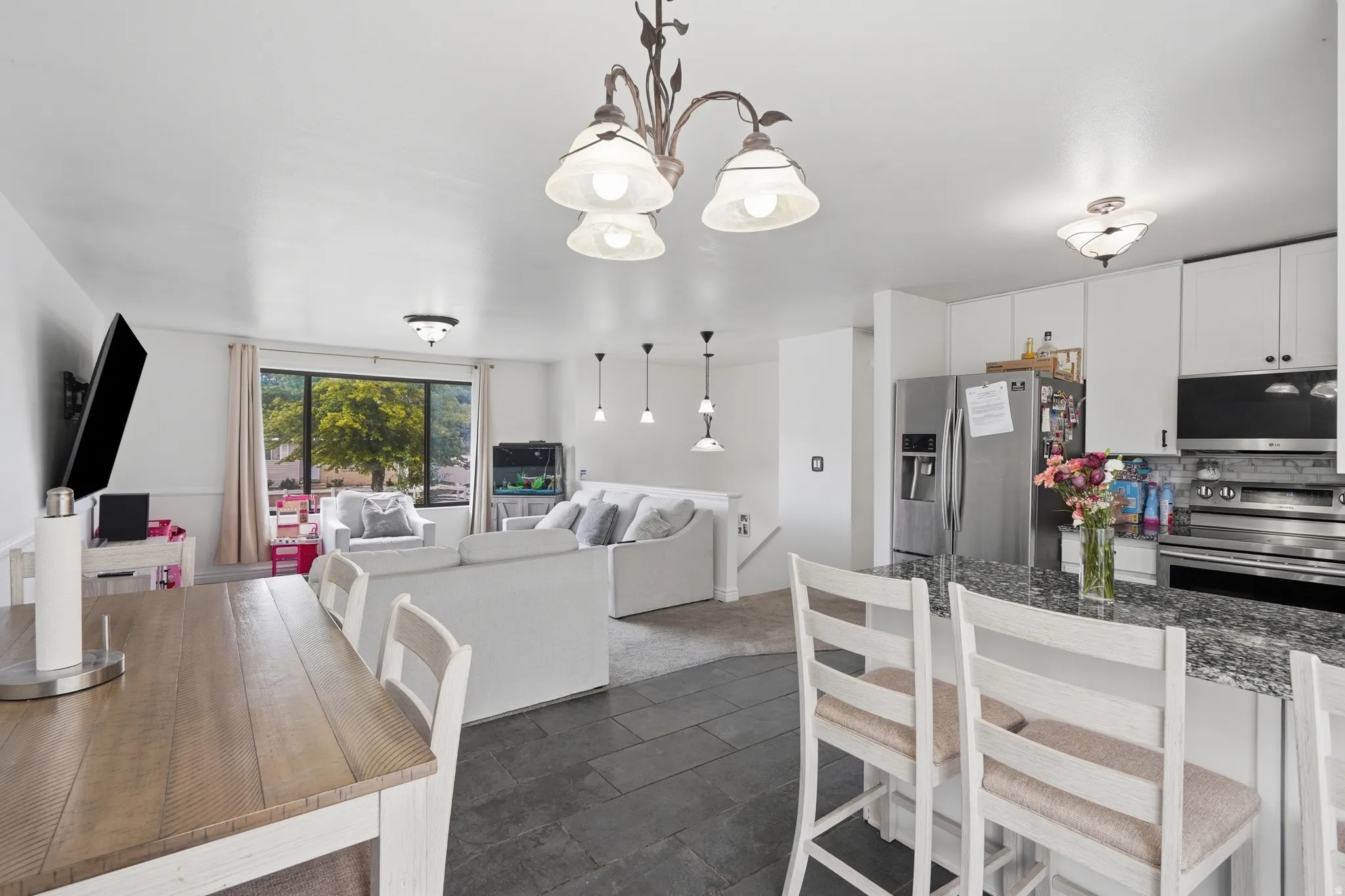 Open-concept living space featuring a kitchen with white cabinetry and stainless steel appliances