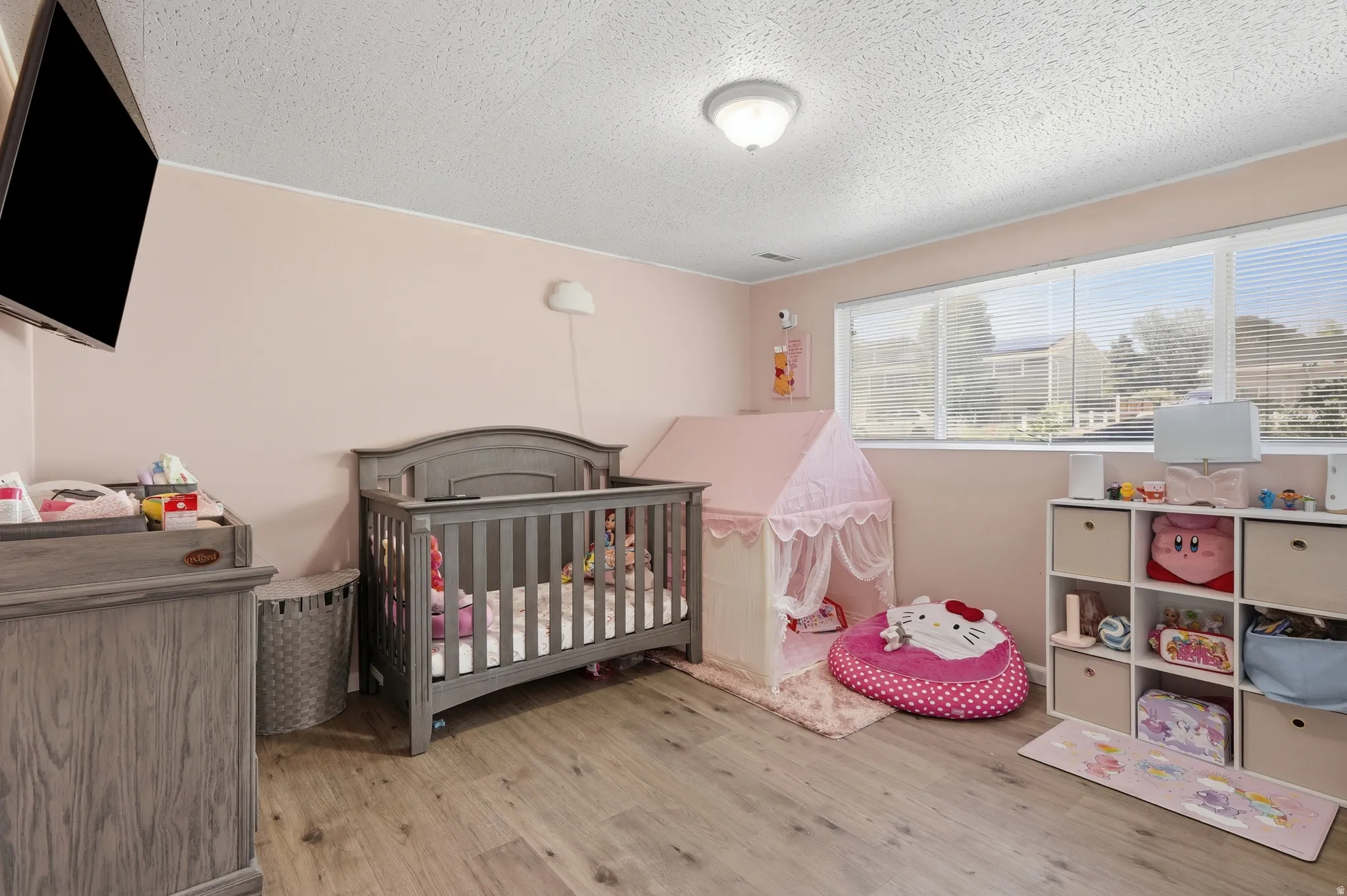 Room featuring light pink walls, wood-finish flooring, recessed lighting, and a large window with horizontal blinds