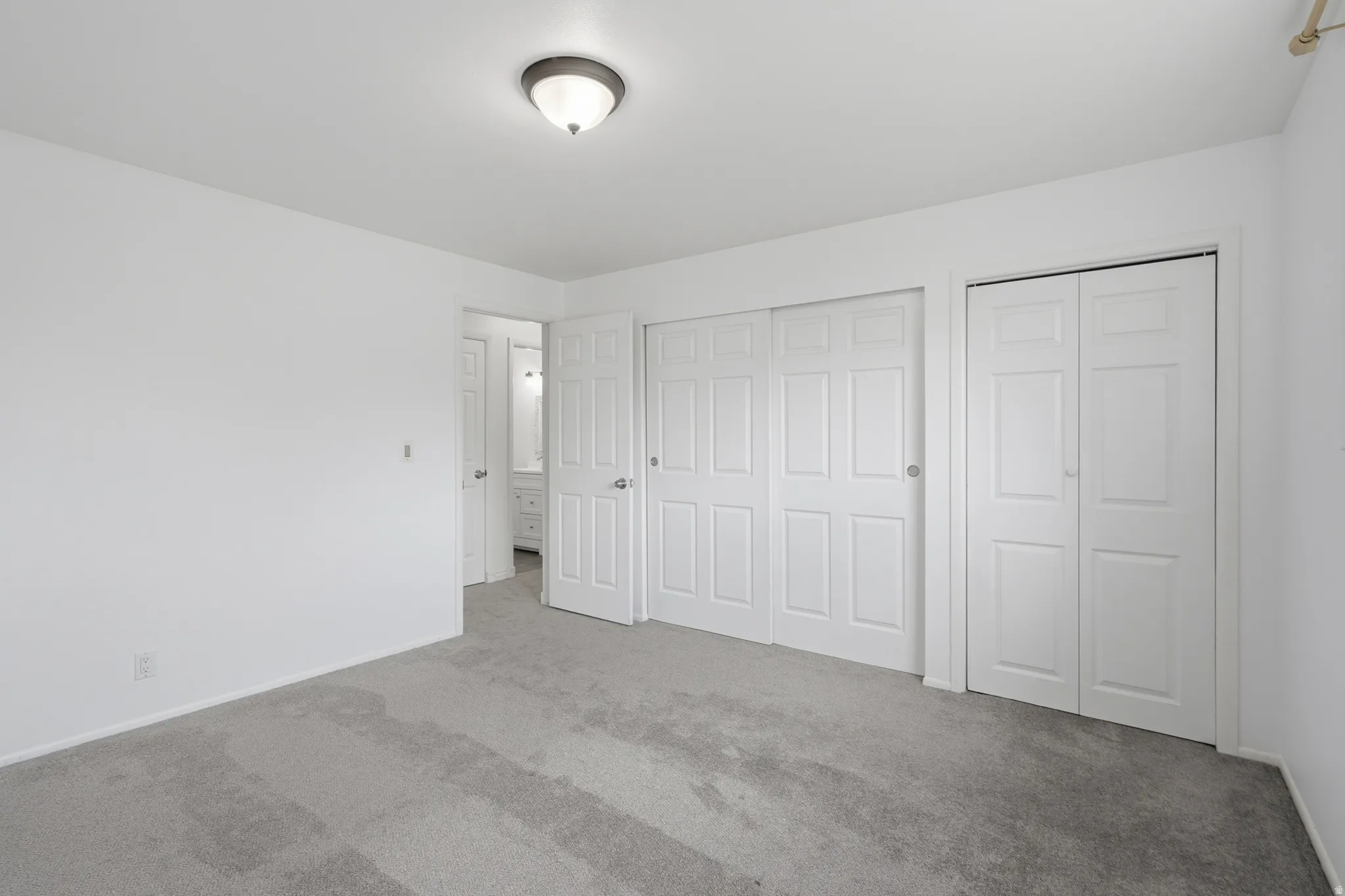 Neutral tone interior featuring plush grey carpeting, white walls, and a semi-flush mount ceiling light