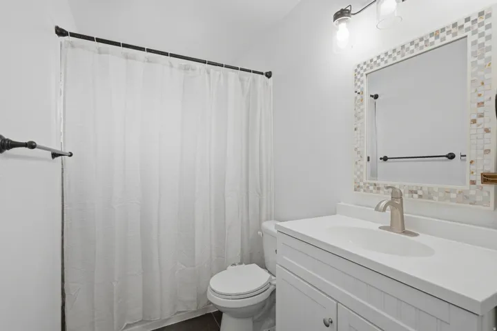 Bathroom featuring a white vanity with integrated sink, brushed nickel faucet, and a tiled mirror frame