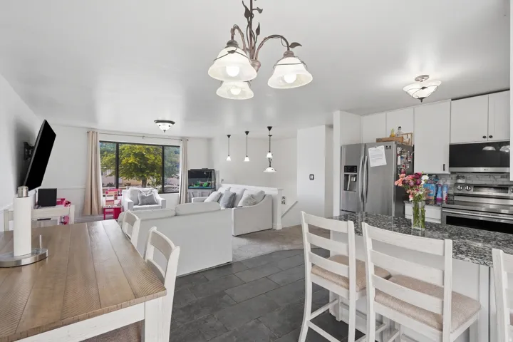 Open-concept living space featuring a kitchen with white cabinetry and stainless steel appliances
