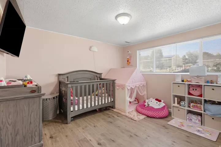Room featuring light pink walls, wood-finish flooring, recessed lighting, and a large window with horizontal blinds