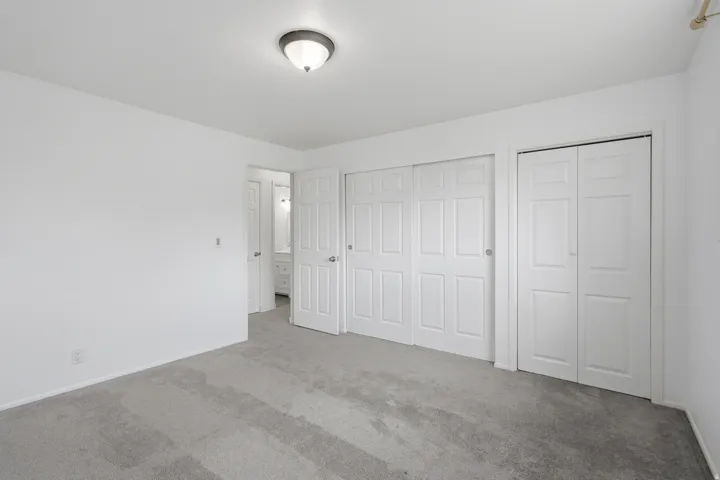 Neutral tone interior featuring plush grey carpeting, white walls, and a semi-flush mount ceiling light
