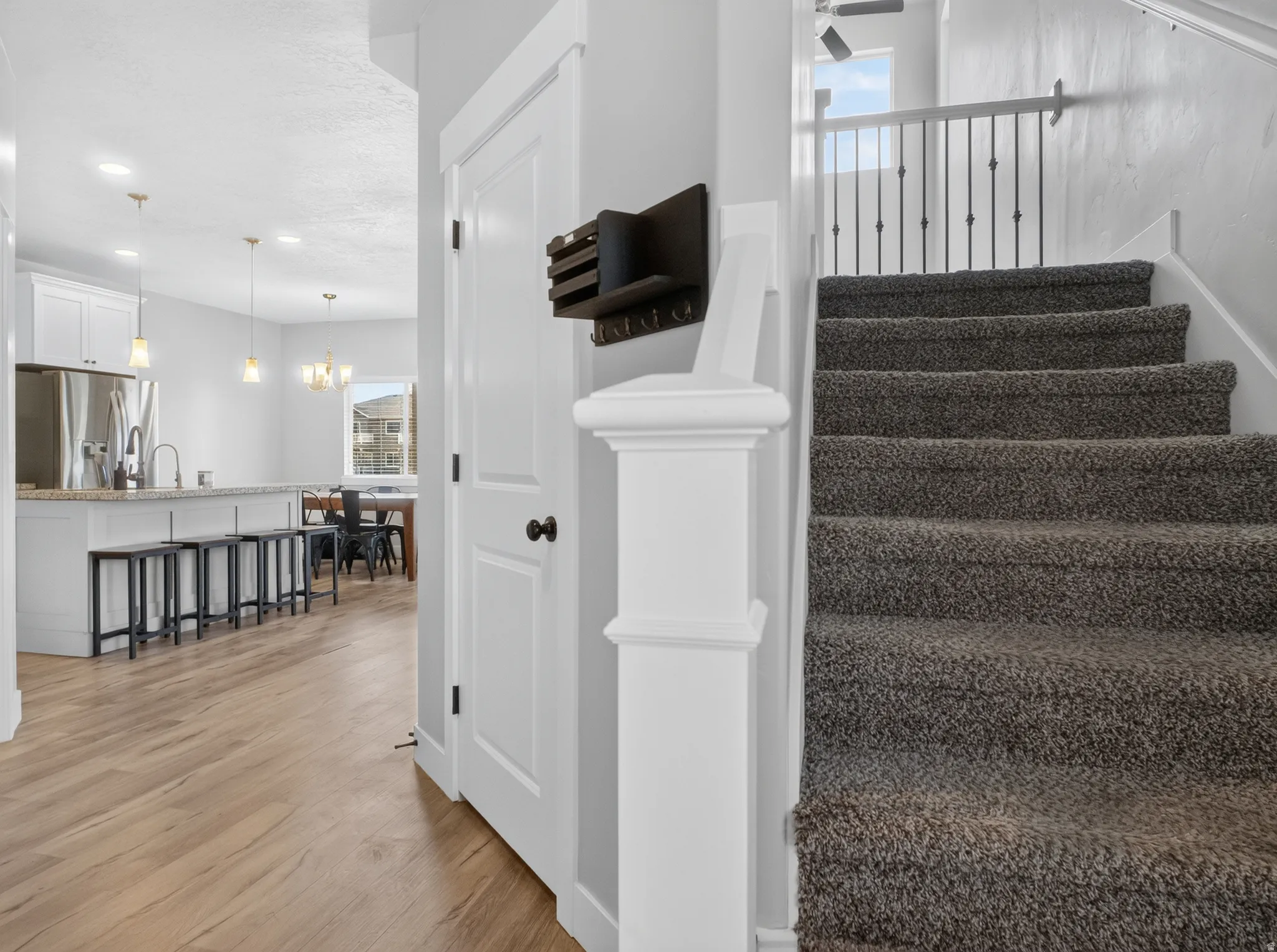 Carpeted staircase with white balusters and wrought iron spindles