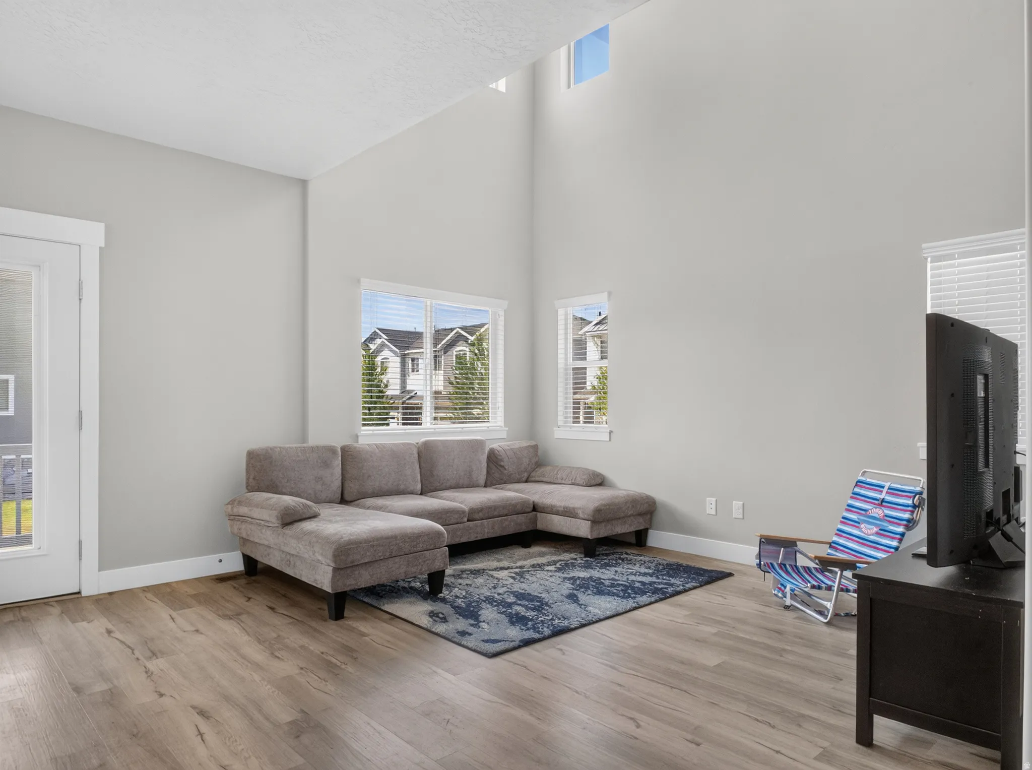 Spacious living area featuring a vaulted ceiling and wood-finish flooring