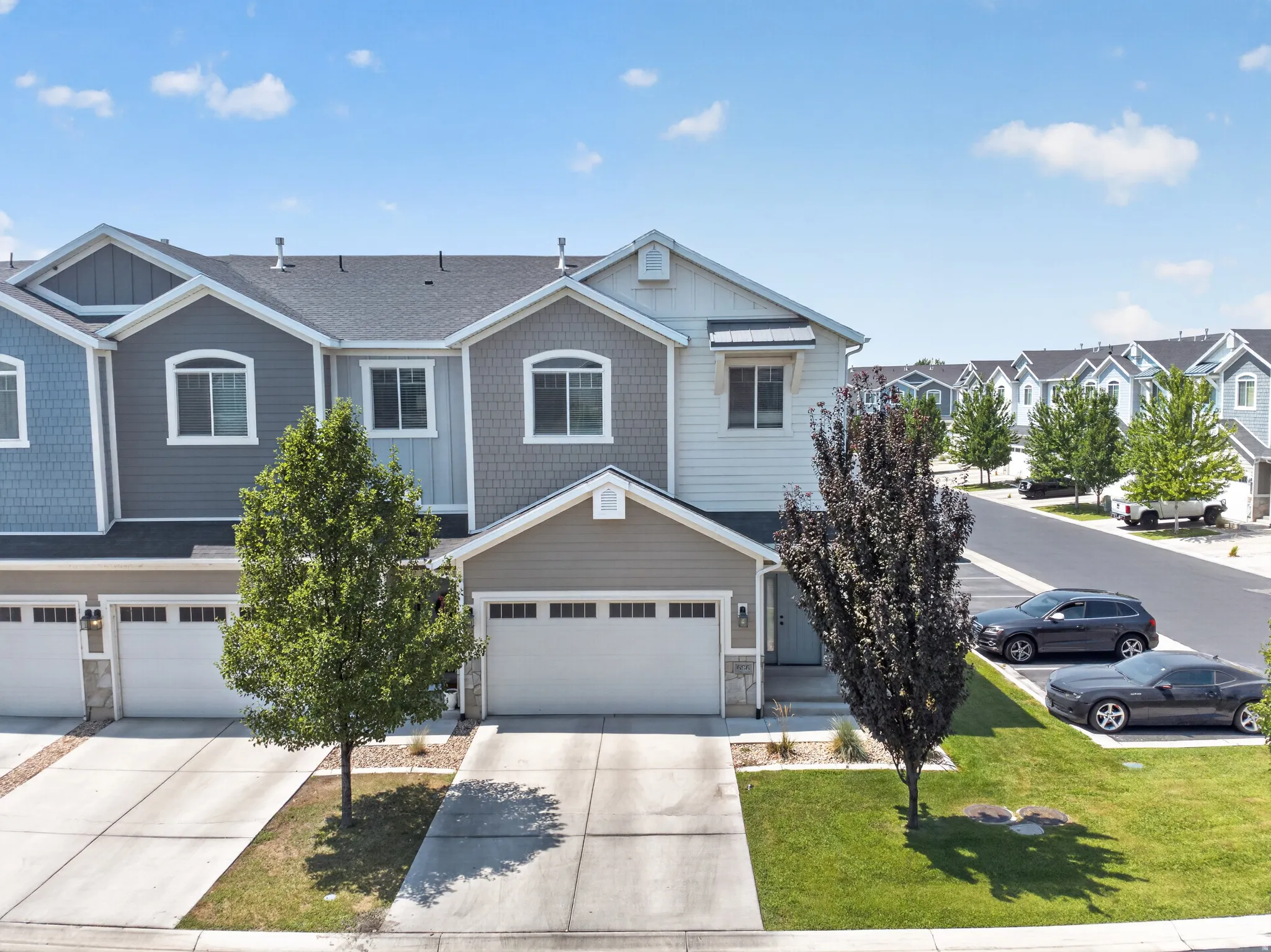 Contemporary townhome featuring a two-car garage, concrete driveway, and covered entry