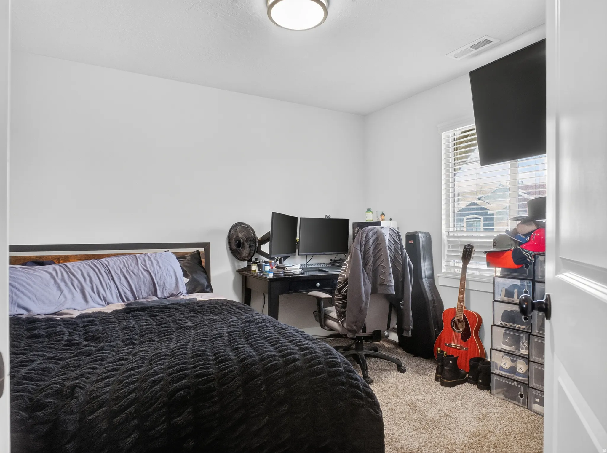 Bedroom featuring neutral wall paint, a single window with horizontal blinds, and a built-in overhead light fixture