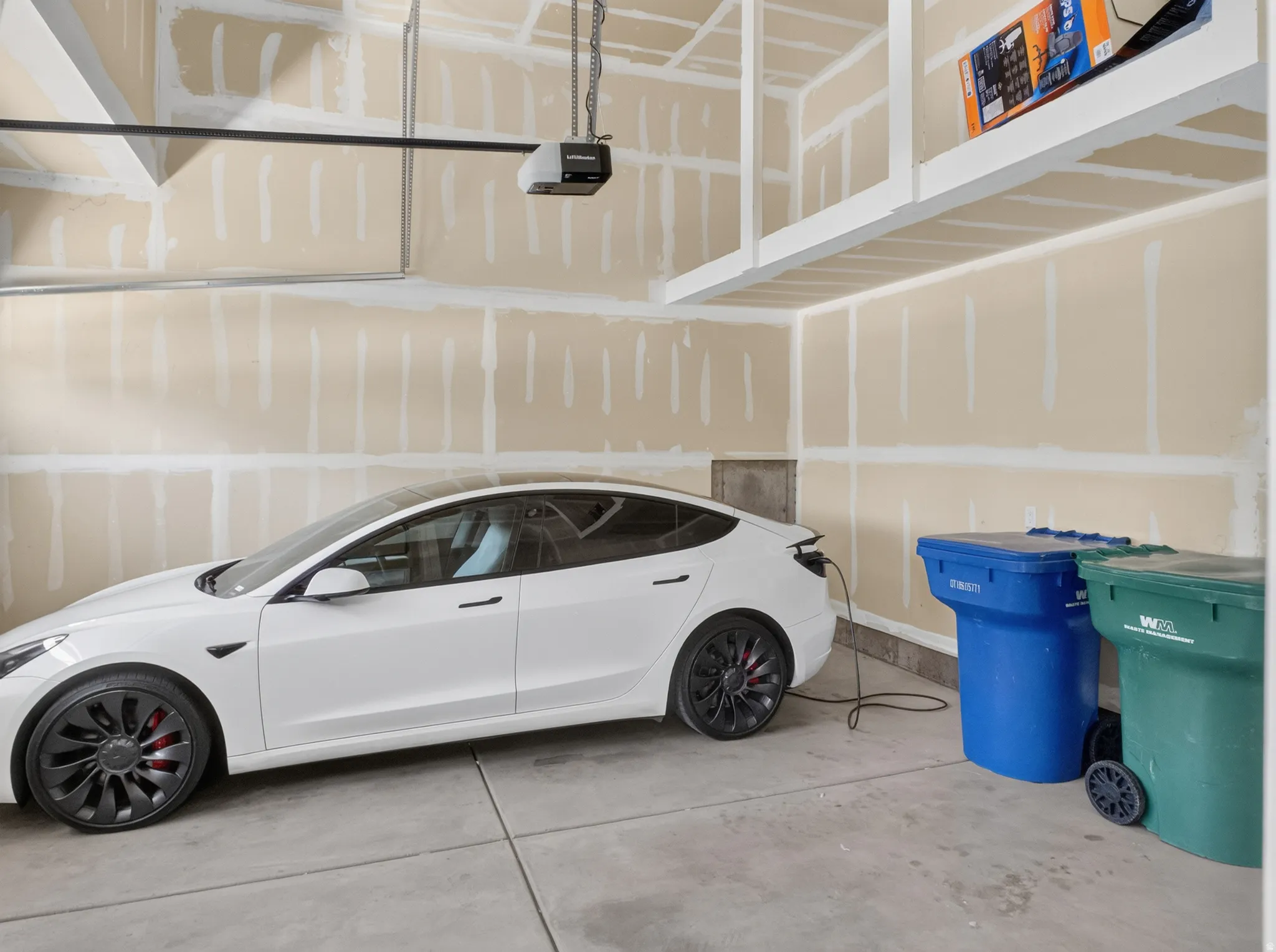 Attached garage featuring a concrete floor, overhead storage shelves, and an electric vehicle charging outlet