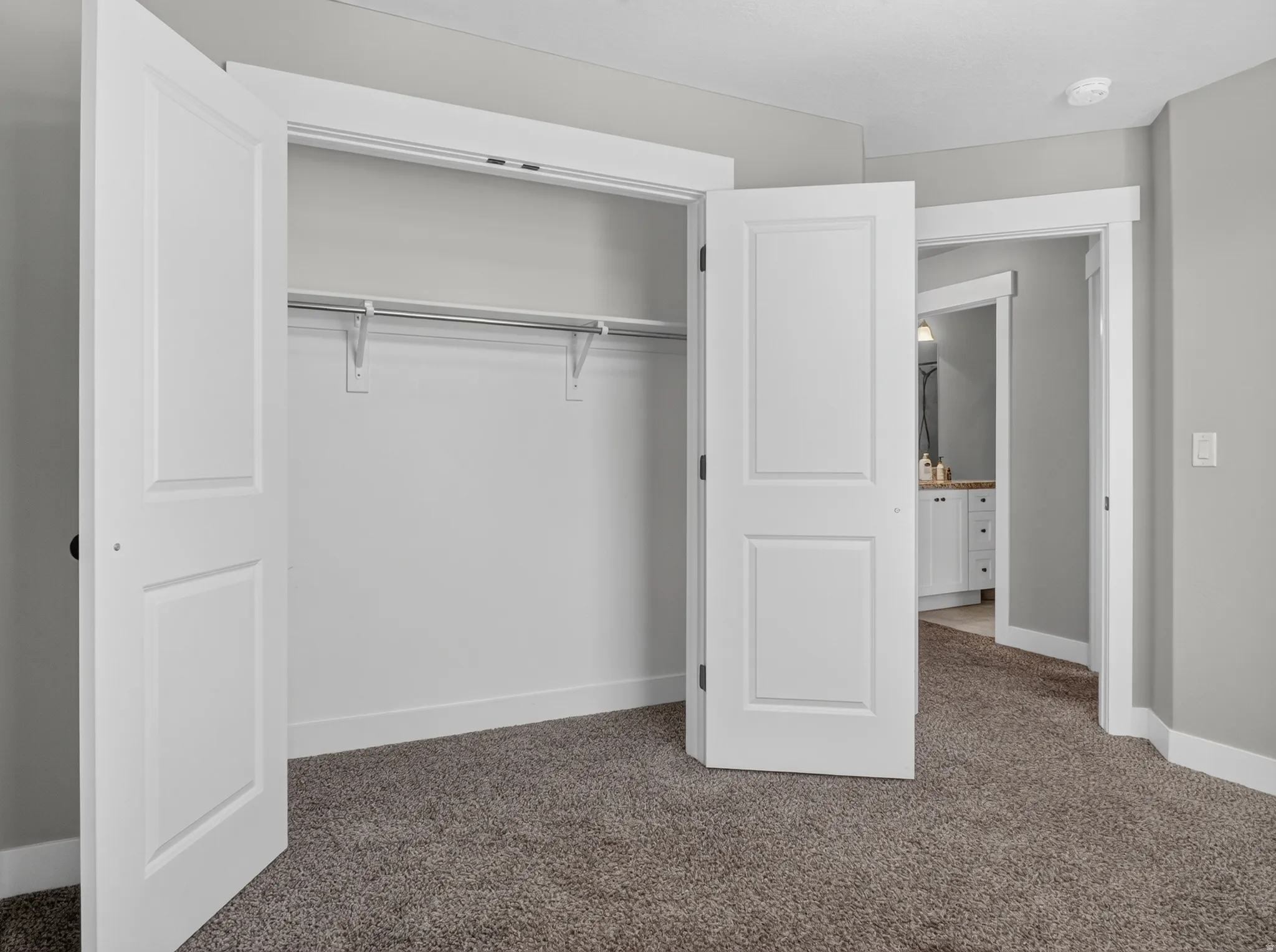 Carpeted room featuring a double-door closet with shelving and hanging rods