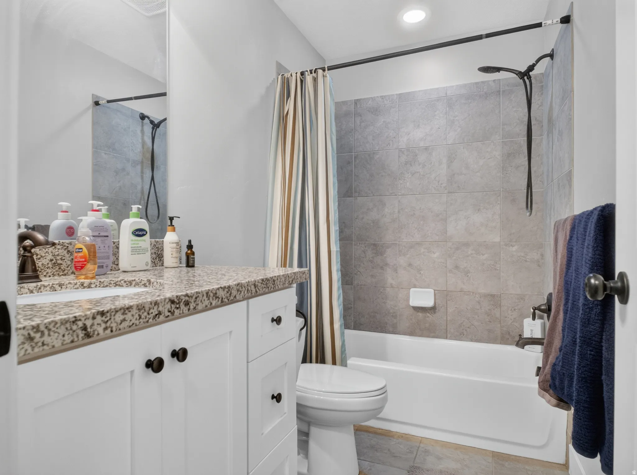 Bathroom featuring a white vanity with a speckled countertop, a drop-in sink, and dark bronze hardware