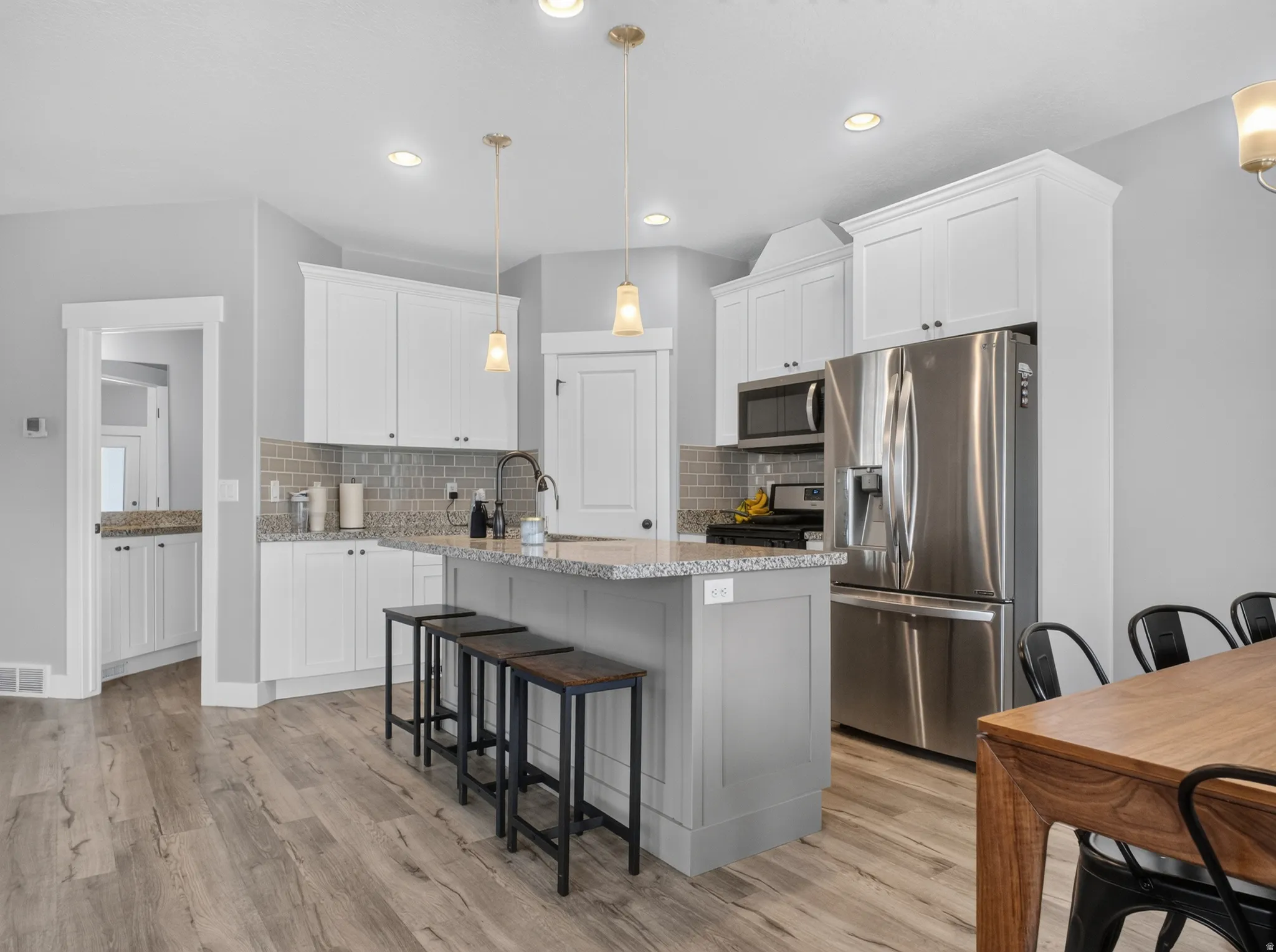 Modern kitchen featuring white shaker cabinetry, speckled countertops, stainless steel appliances, a tiled backsplash, and recessed lighting