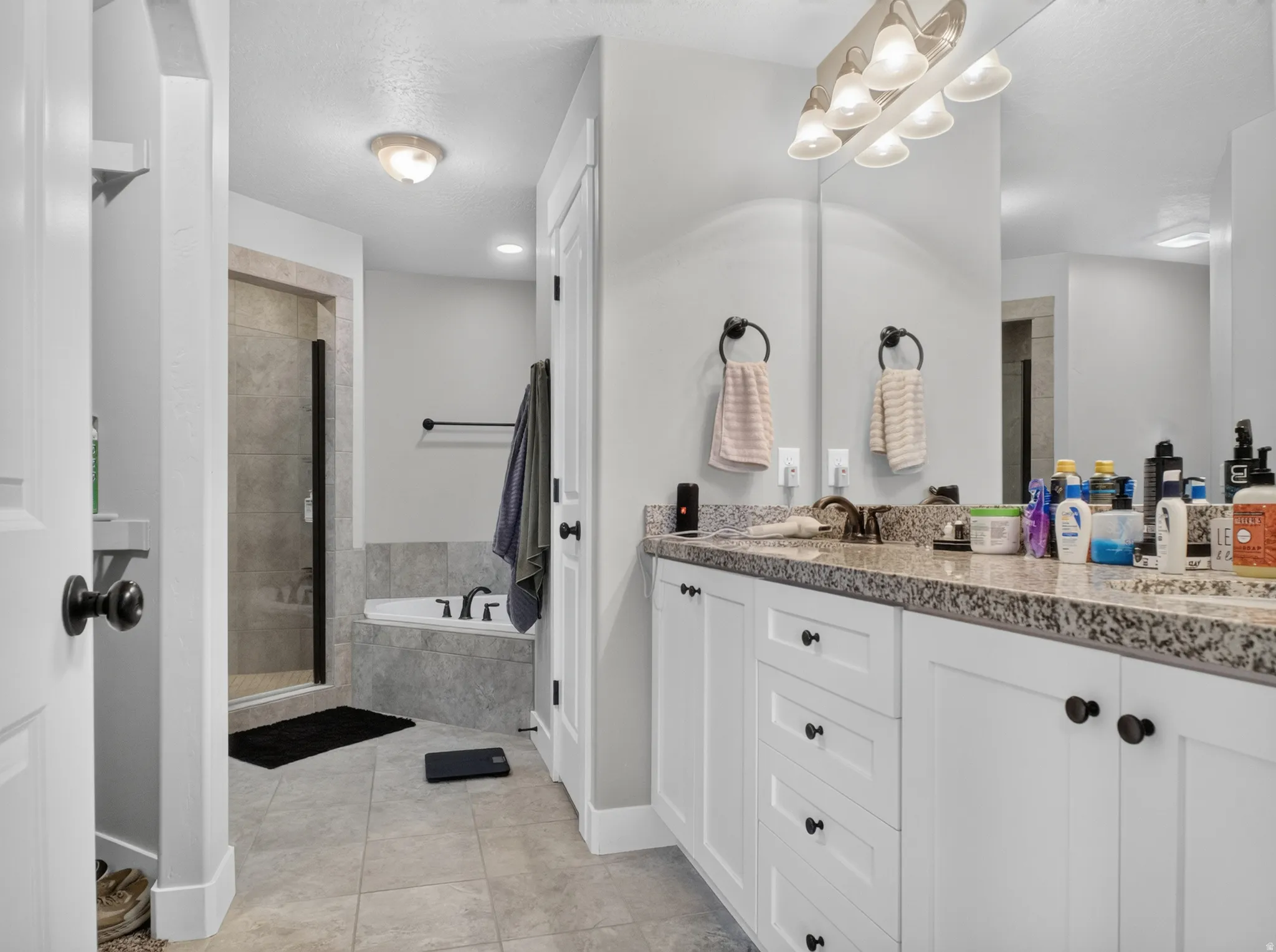 Bathroom featuring a double vanity with white cabinetry and a speckled countertop