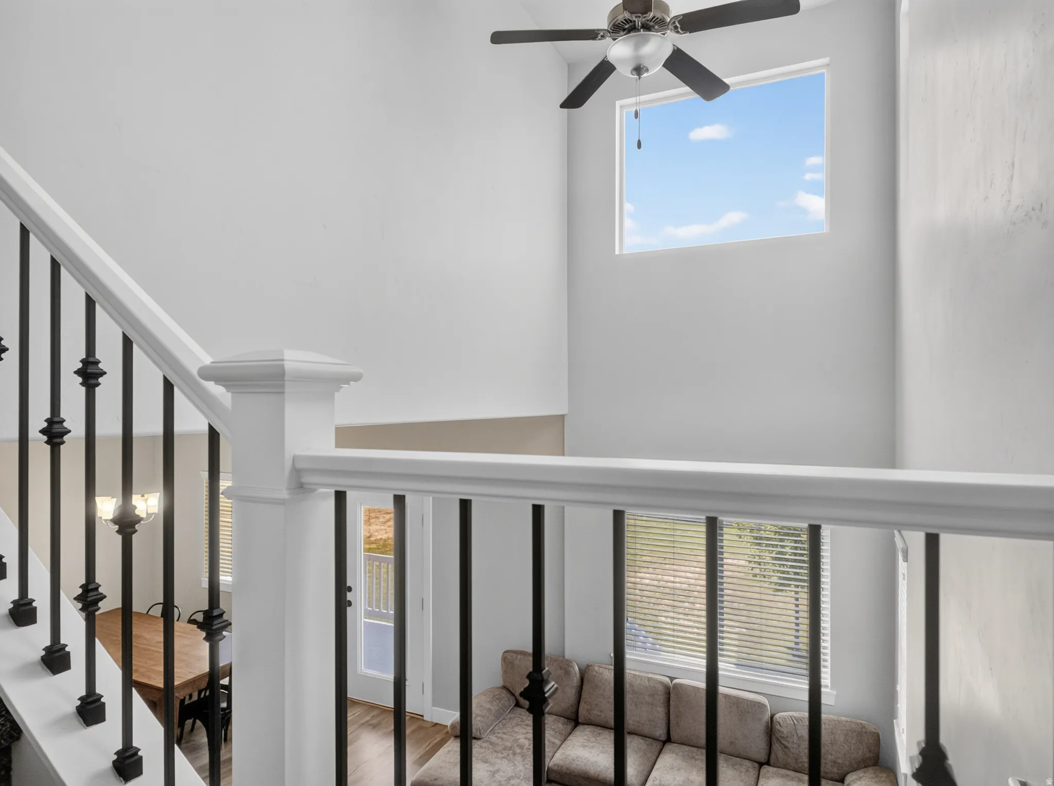 Two-story volume ceiling featuring a ceiling fan and upper window