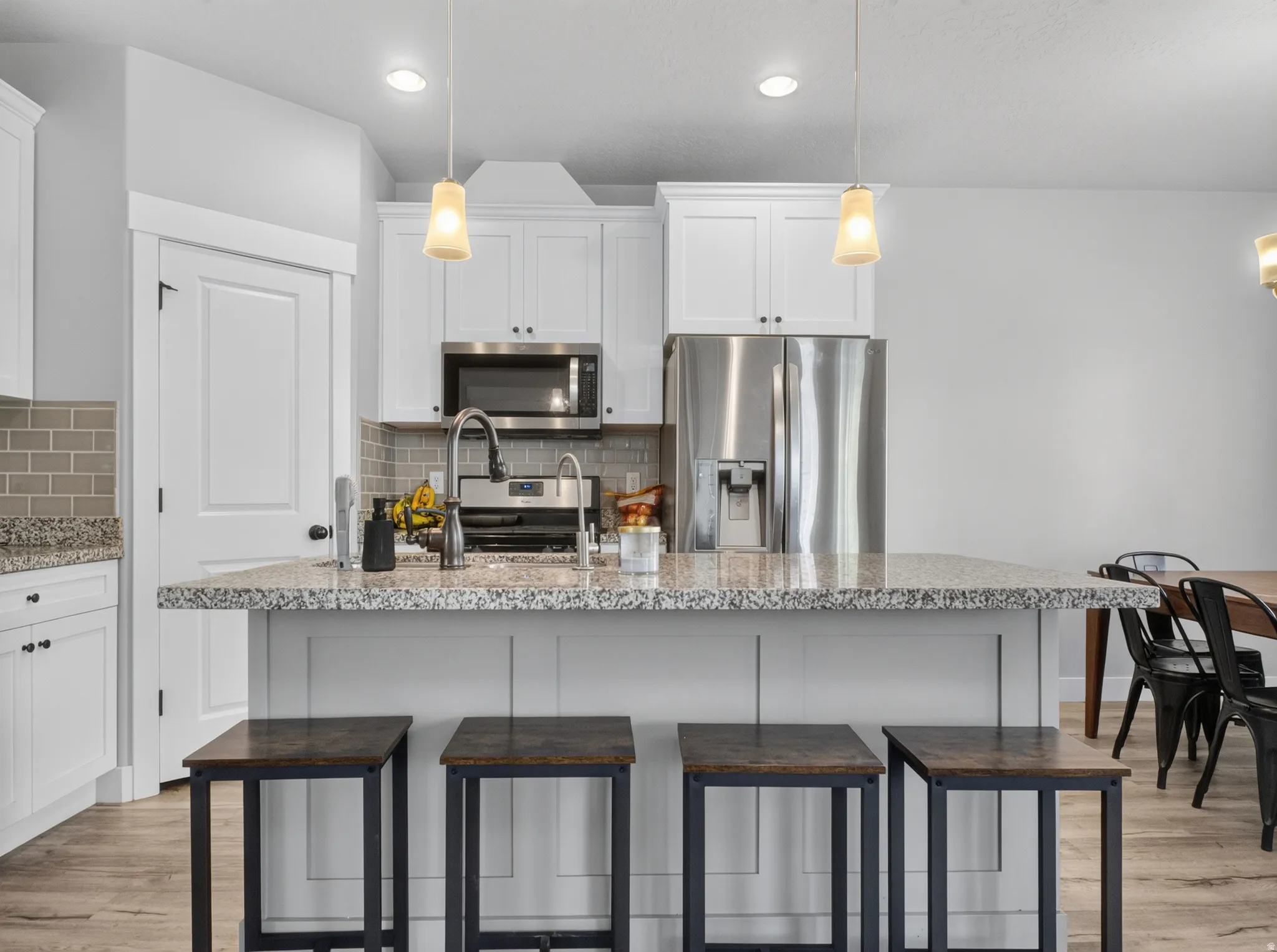 Kitchen island featuring a granite-style countertop, built-in paneling, and pendant lighting