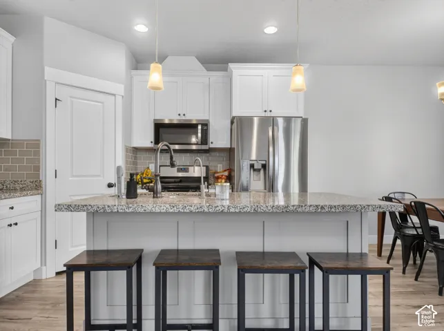 Kitchen island featuring a granite-style countertop, built-in paneling, and pendant lighting