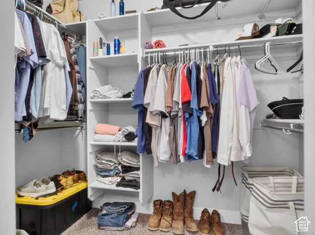 Expansive walk-in closet featuring white built-in shelving, multiple hanging rods, and an integrated wire shelving system