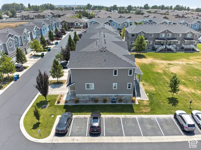 Contemporary townhouse with gray siding and stone accents, featuring a dedicated parking area, manicured landscaping, and a spacious grassy area to the side