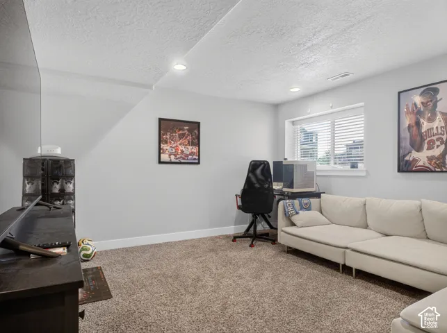 Carpeted living space with recessed lighting and a window featuring blinds