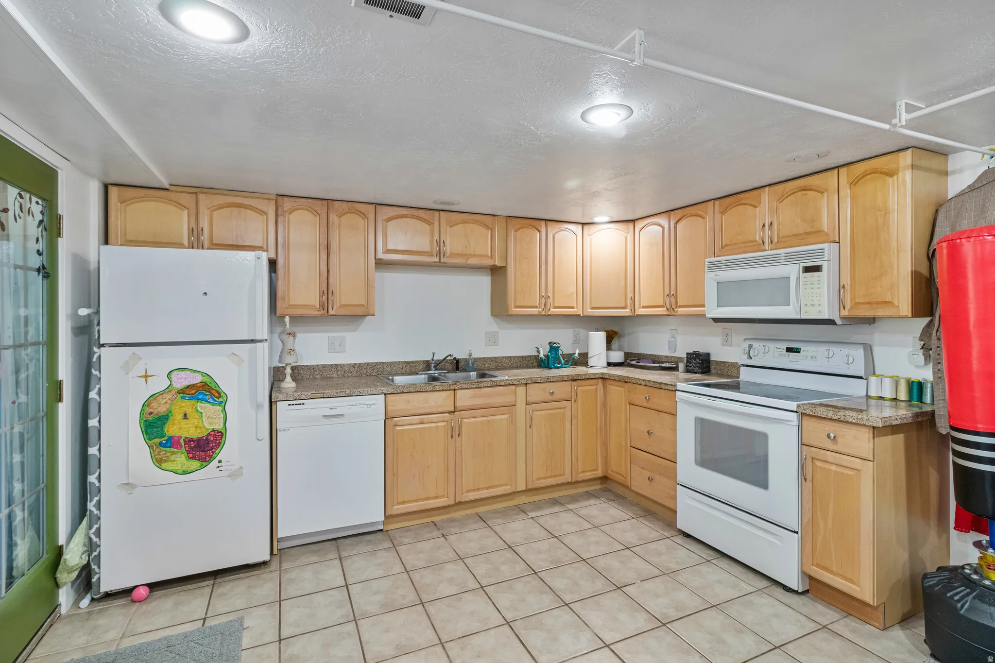 Kitchen featuring light wood cabinetry, stone-finish countertops, and tile flooring