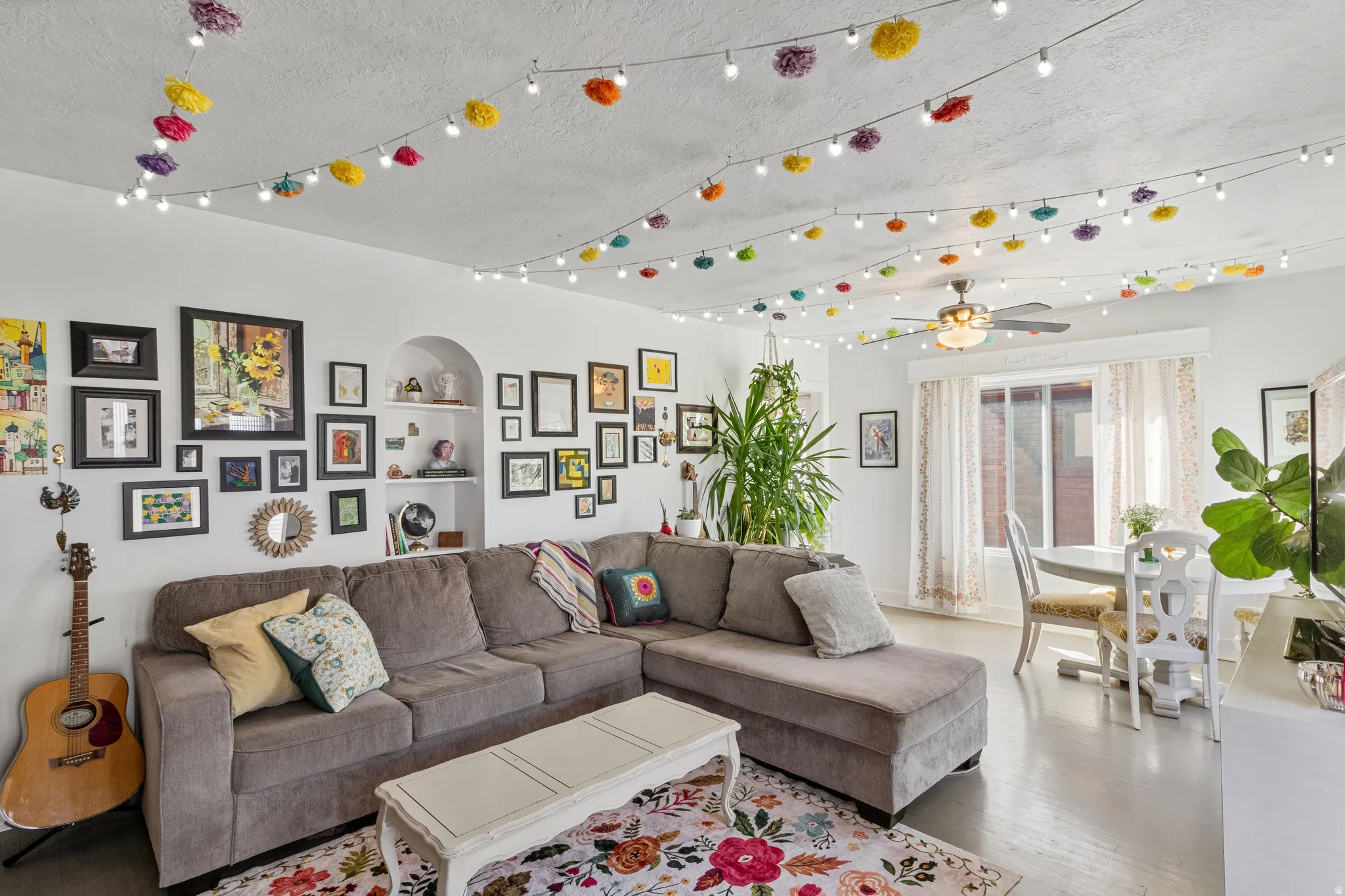 Open-concept living space featuring light-toned flooring and a built-in arched alcove with shelving