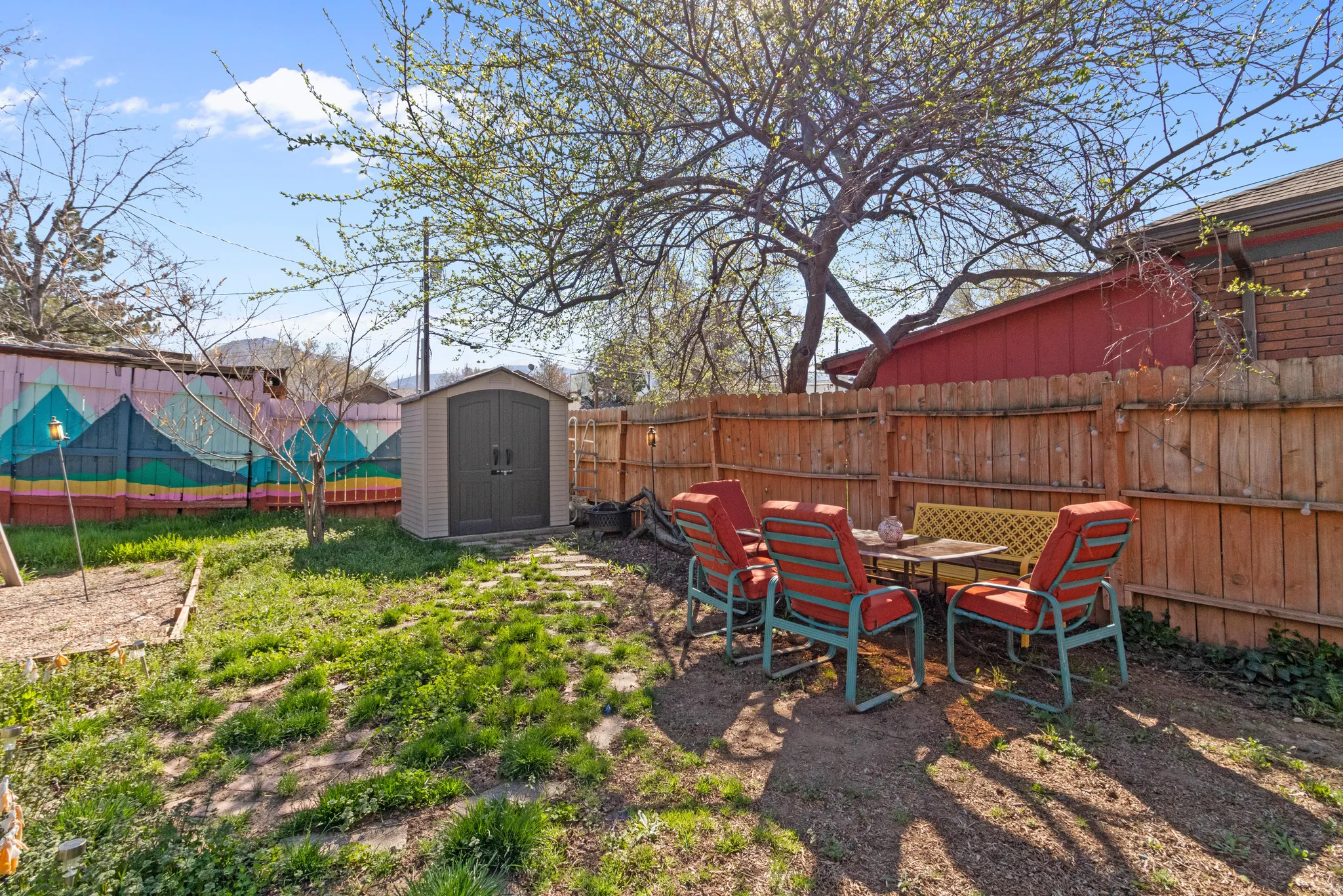 Expansive backyard featuring a privacy fence, established trees, and a utility shed