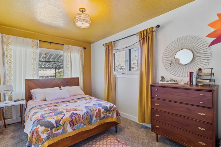 Bedroom featuring a wood-finish bed frame with a chevron-patterned headboard, textured ceiling, and a modern drum pendant light fixture