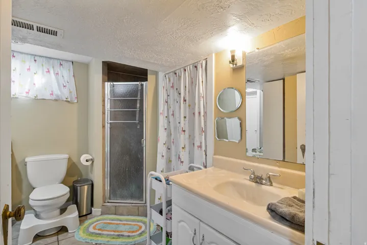 Bathroom featuring a single vanity with integrated sink, chrome faucet, and wall-mounted lighting fixture