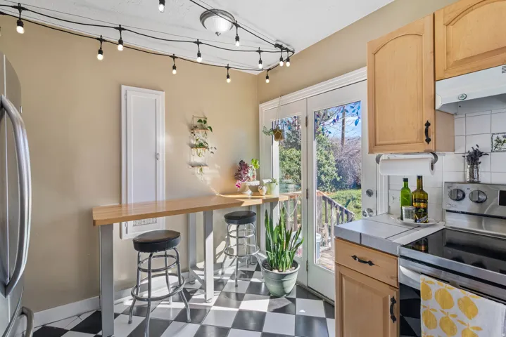 Kitchen dining area featuring black and white checkered flooring, a light wood-finish breakfast bar, and French doors providing direct outdoor access