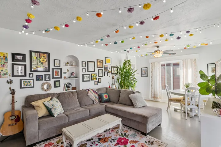 Open-concept living space featuring light-toned flooring and a built-in arched alcove with shelving