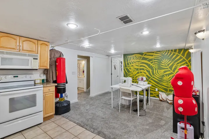 Kitchenette with wood cabinetry, white appliances, and light-toned tile flooring