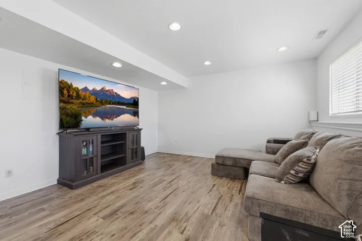 Entertainment-focused media room featuring a wall-mounted flat-screen television, dark wood cabinetry with glass-front display shelving, and recessed ceiling lighting