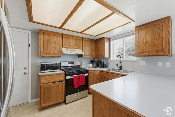 Warm wood cabinetry and white quartz countertops define this spacious kitchen, featuring stainless steel appliances including a gas range and microwave, an undermount sink with pull-down faucet, and abundant storage