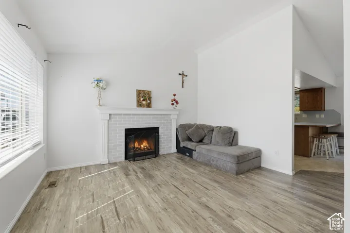 Bright living room featuring wood-finish flooring, a gas fireplace with white surround and mantel, and built-in shelving