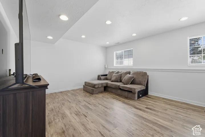 Finished basement recreation room featuring wood-finish flooring, recessed ceiling lighting, and wainscoting detail
