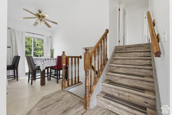 Welcoming foyer showcasing a wooden staircase with turned balusters and a natural wood handrail, wide-plank wood-finish flooring throughout, and abundant natural light from a multi-pane window