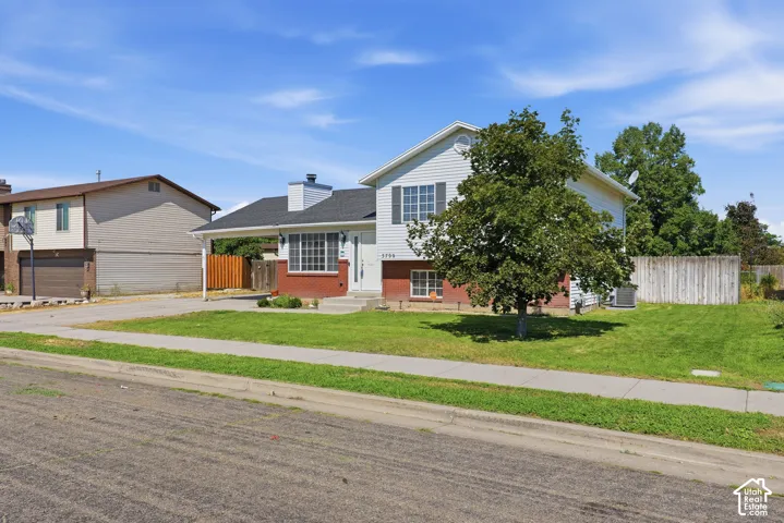Charming two-story residence featuring a brick and siding exterior, two-car attached garage, and a manicured front lawn anchored by mature shade trees