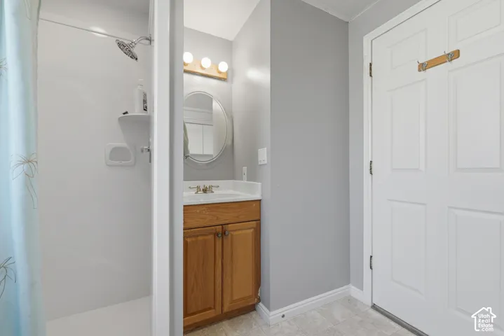 Full bathroom featuring a single vanity with wood-finish cabinetry, a white countertop, a circular mirror, and a white shower-tub combination