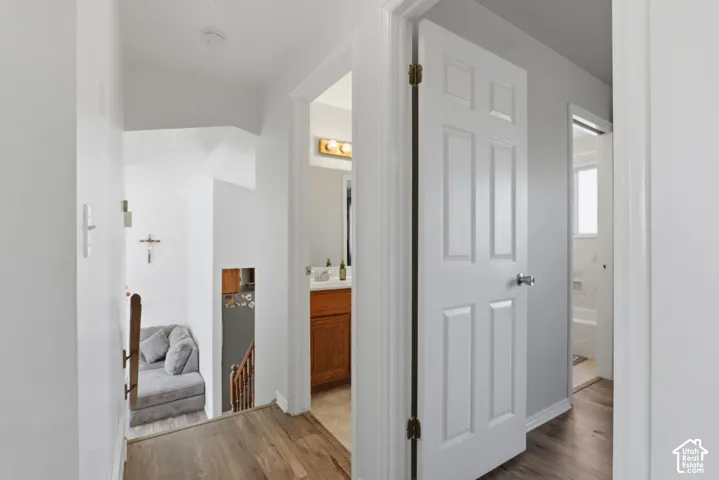 Hallway featuring white six-panel doors with oil-rubbed bronze hardware, wood-finish flooring, and clean white walls with gray ceiling detail