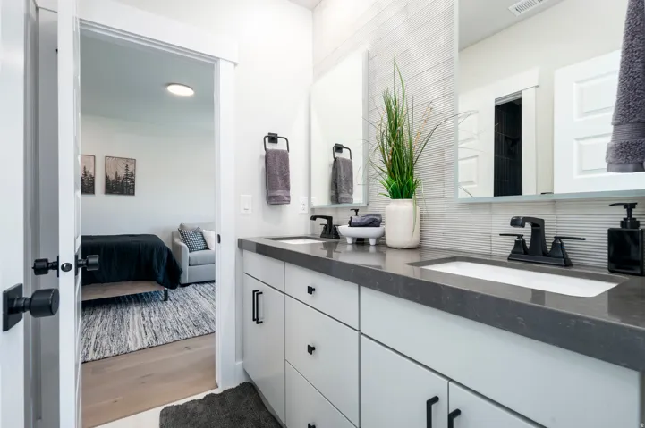 Dual vanity with matte black fixtures, integrated sinks, white cabinetry, and a dark countertop