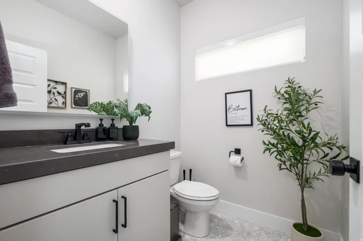 Integrated vanity with a dark countertop and undermount sink, matte black faucet, and white cabinetry
