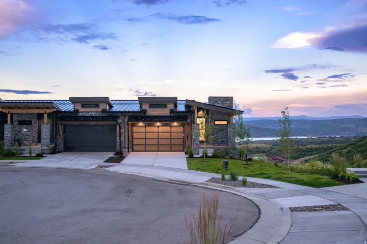 Modern exterior with stone accents, a metal roof, and an attached garage