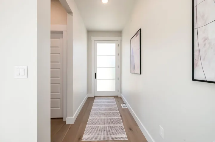 Bright hallway with wood-finish flooring, recessed lighting, and clean white walls