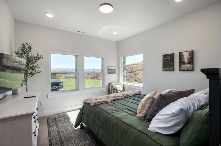 Recessed lighting, wood-finish flooring, multiple windows, and a black-finish headboard