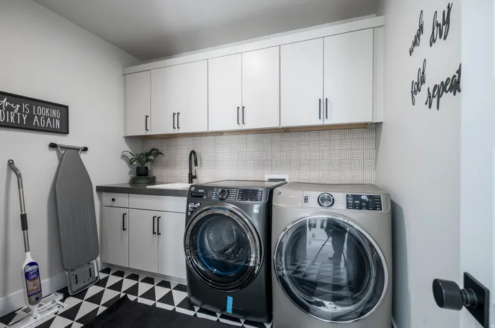 White upper cabinetry with black hardware, complementing a dark countertop and undermount sink