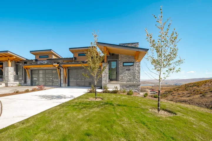 Modern residential home featuring a striking mixed-material exterior with natural stone and warm wood accents, complemented by a multi-level roofline with clean architectural lines