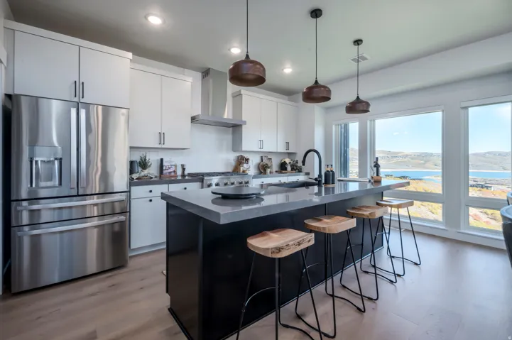 Modern kitchen featuring white cabinetry, stainless steel appliances, a large center island with countertop seating, and light wood-finish flooring
