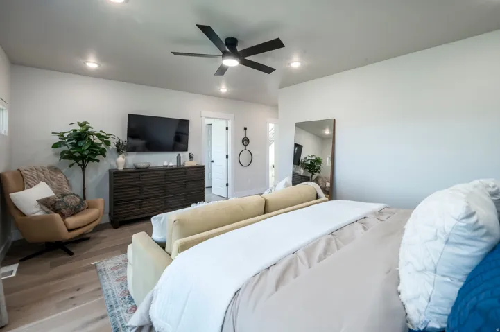Spacious primary bedroom featuring wood-finish flooring, recessed lighting, and a ceiling fan with integrated light fixture