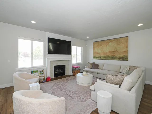 Sophisticated living room featuring a gas fireplace with surround mantel, recessed ceiling lighting, and wood-finish flooring throughout