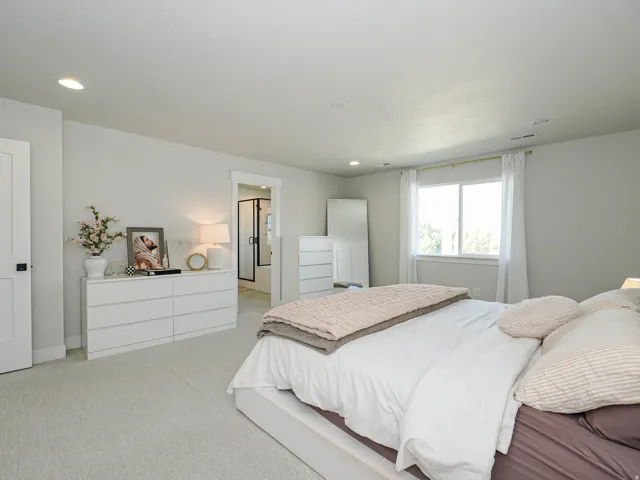 Recessed lighting, large window with natural light, light-colored walls, carpeted flooring, and a white interior door