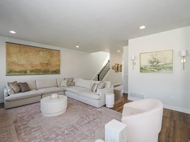 Sophisticated living room featuring a sectional layout with neutral upholstery, recessed ceiling lighting, and wood-finish flooring throughout